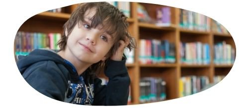 Young boy in a library with hand rested against his head
